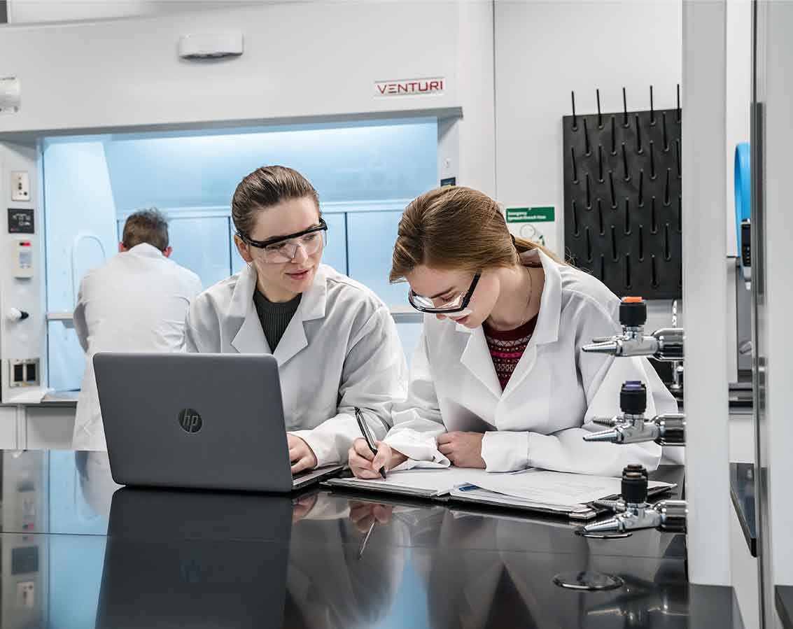 Two students share a computer while in a lab setting