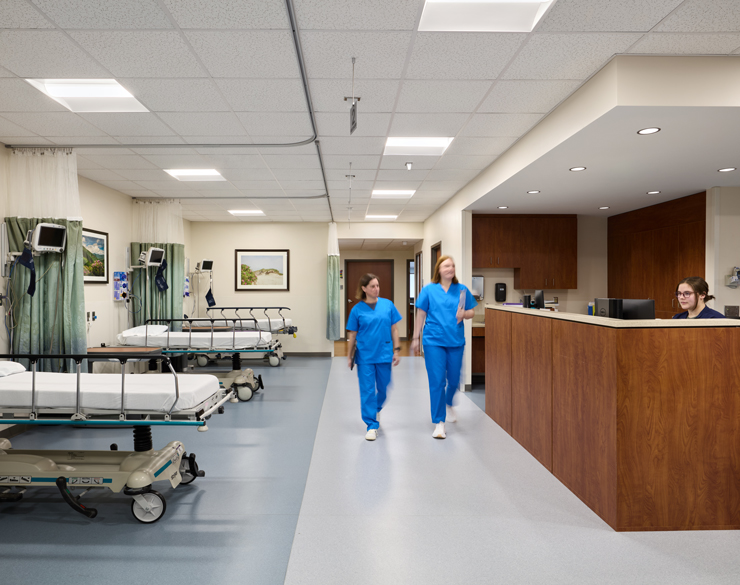 Two healthcare providers walk past the central care station