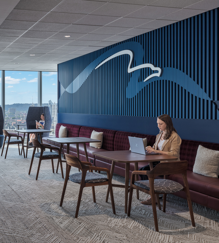 An employee works on their laptop in an open collaboration area