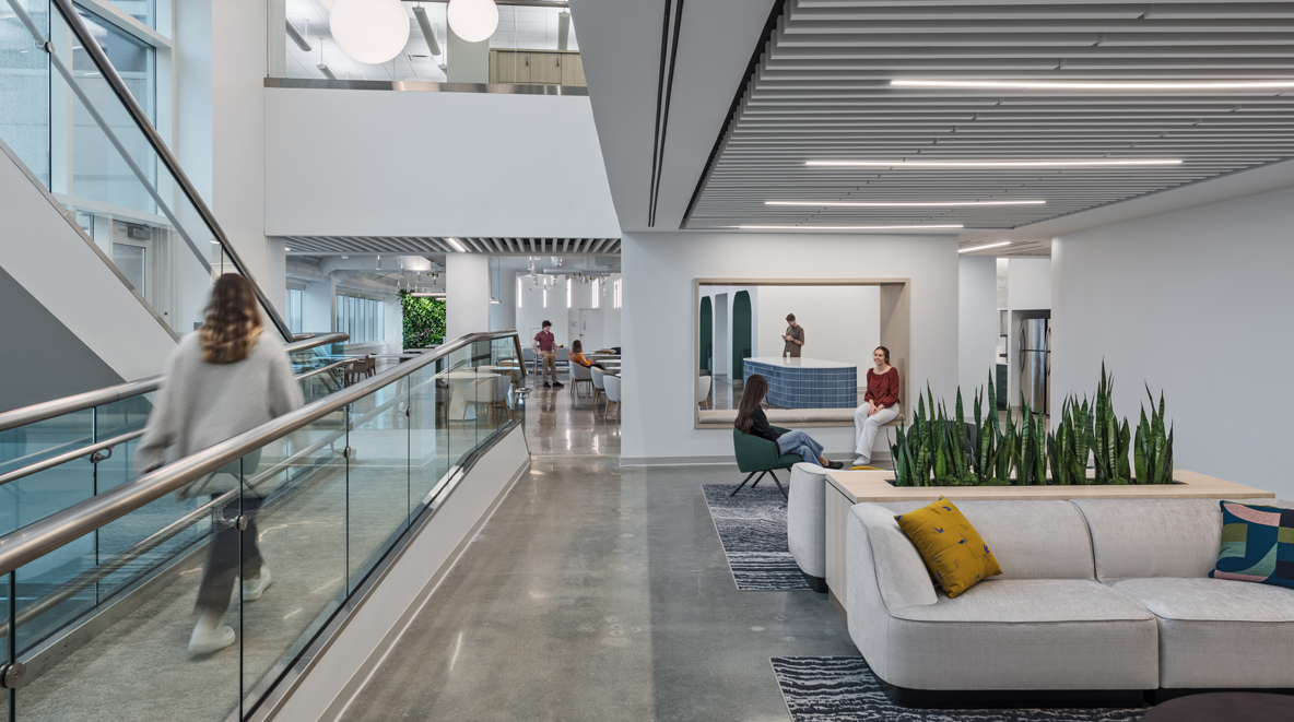 A connecting staircase stands to the left of a large, open collaboration area