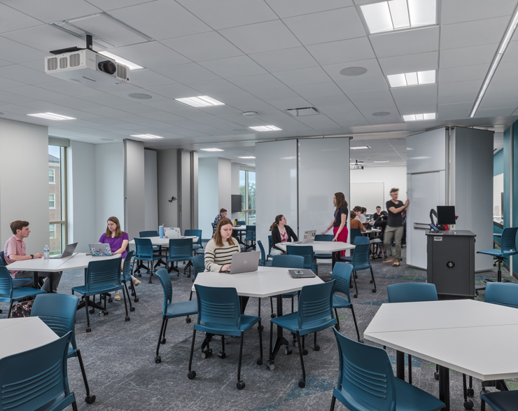 Students sit at tables in small groups