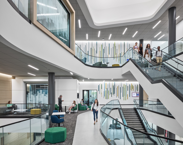 A large, grand staircase extends three floors with collaborative areas flanking it