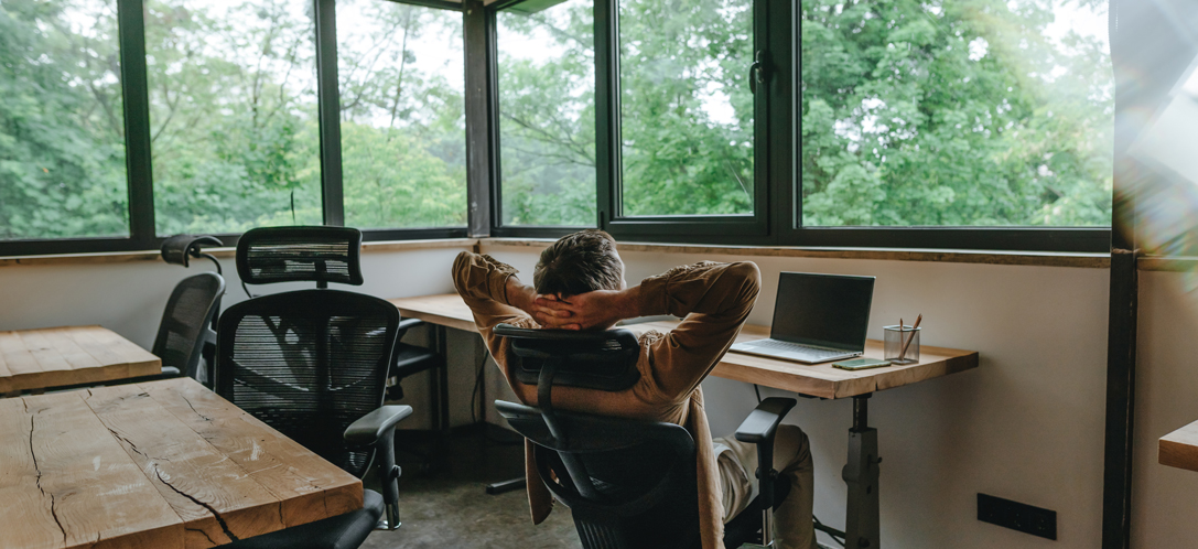 A person works at a desk with big windows and open views.