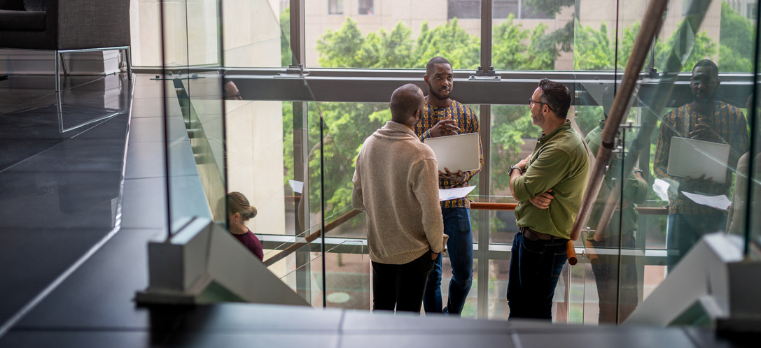 A group of people talk on an open, communicating stair. 