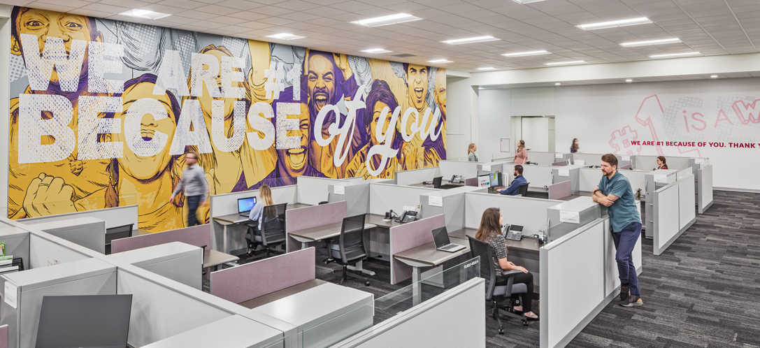 "We are #1 because of you" is displayed on a wall behind a work environment