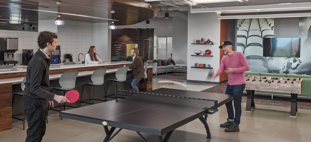 Employees play ping pong in an employee amenity space