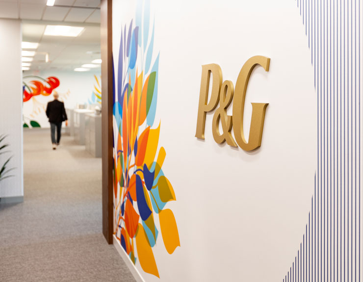Gold P&G logo appears on wall with bright floral mural at Charlotte office
