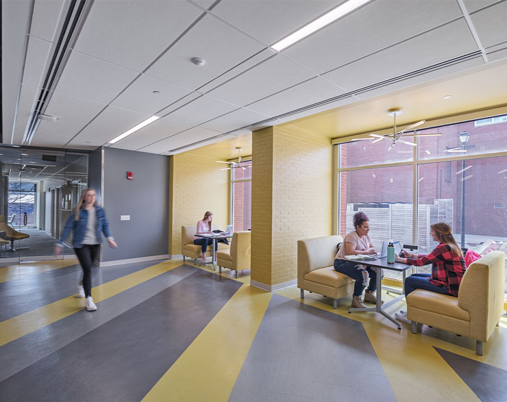 Large yellow booths line the wall of a corridor, providing space for students to gather