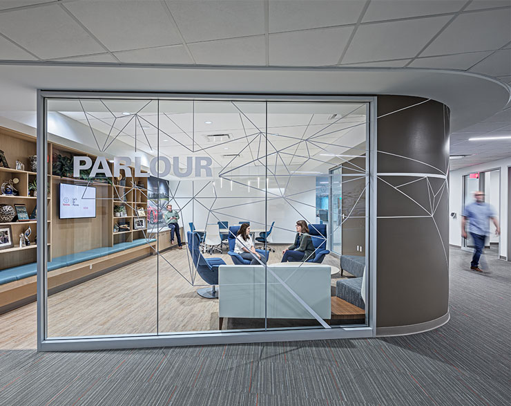 Employees collaborate behind a clear glass wall with privacy vinyl