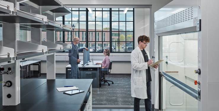 A researcher stands inside a lab with a transparent glass wall