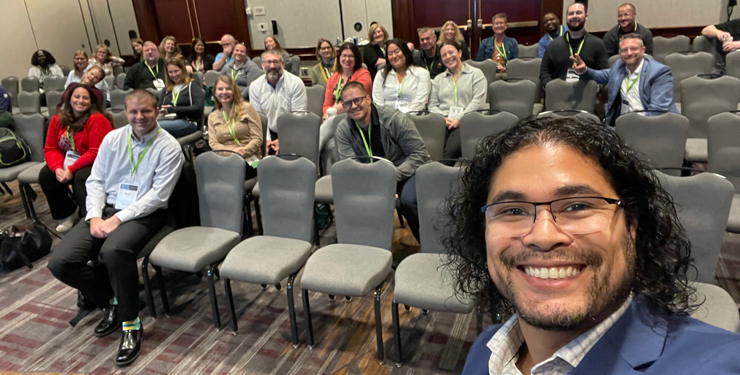 Alejandro Medina snaps a selfie in front of the attendees for his speaking session