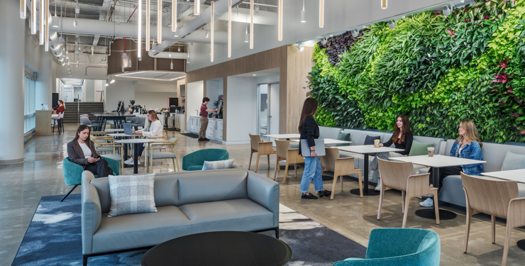 Employees gather in a collaboration area that is backed by a large living wall