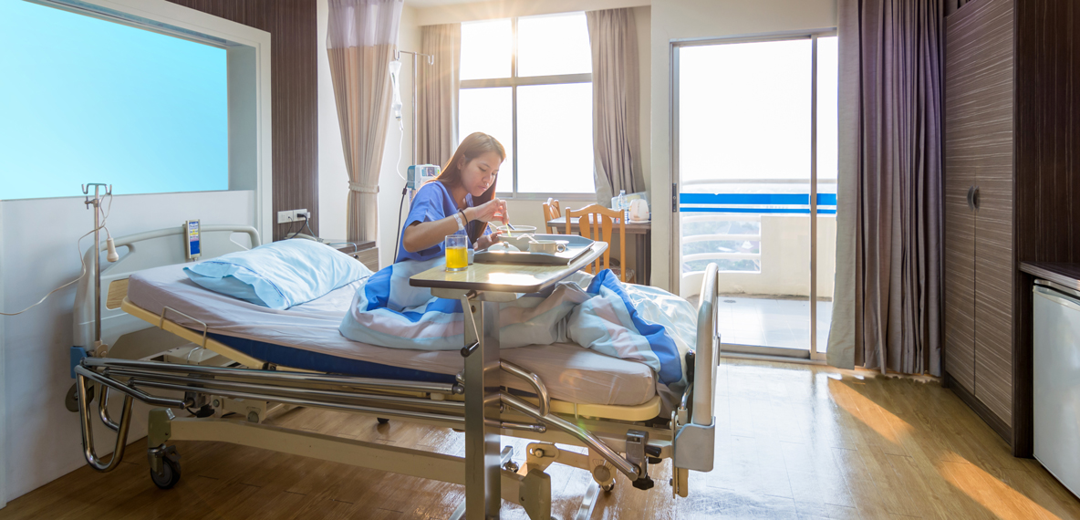 A patient sits in their bed eating off a tray of food